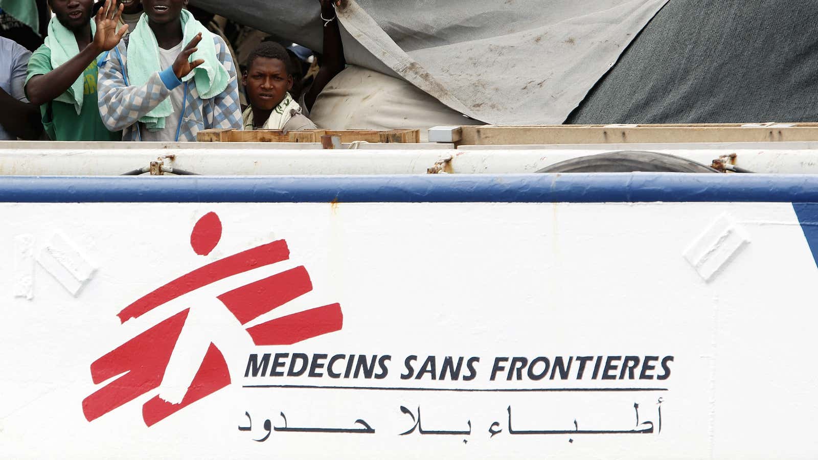 Migrants wave before to be disembarking from a Medecins Sans Frontieres ship carrying 320 migrants in the Sicilian harbor of Augusta.