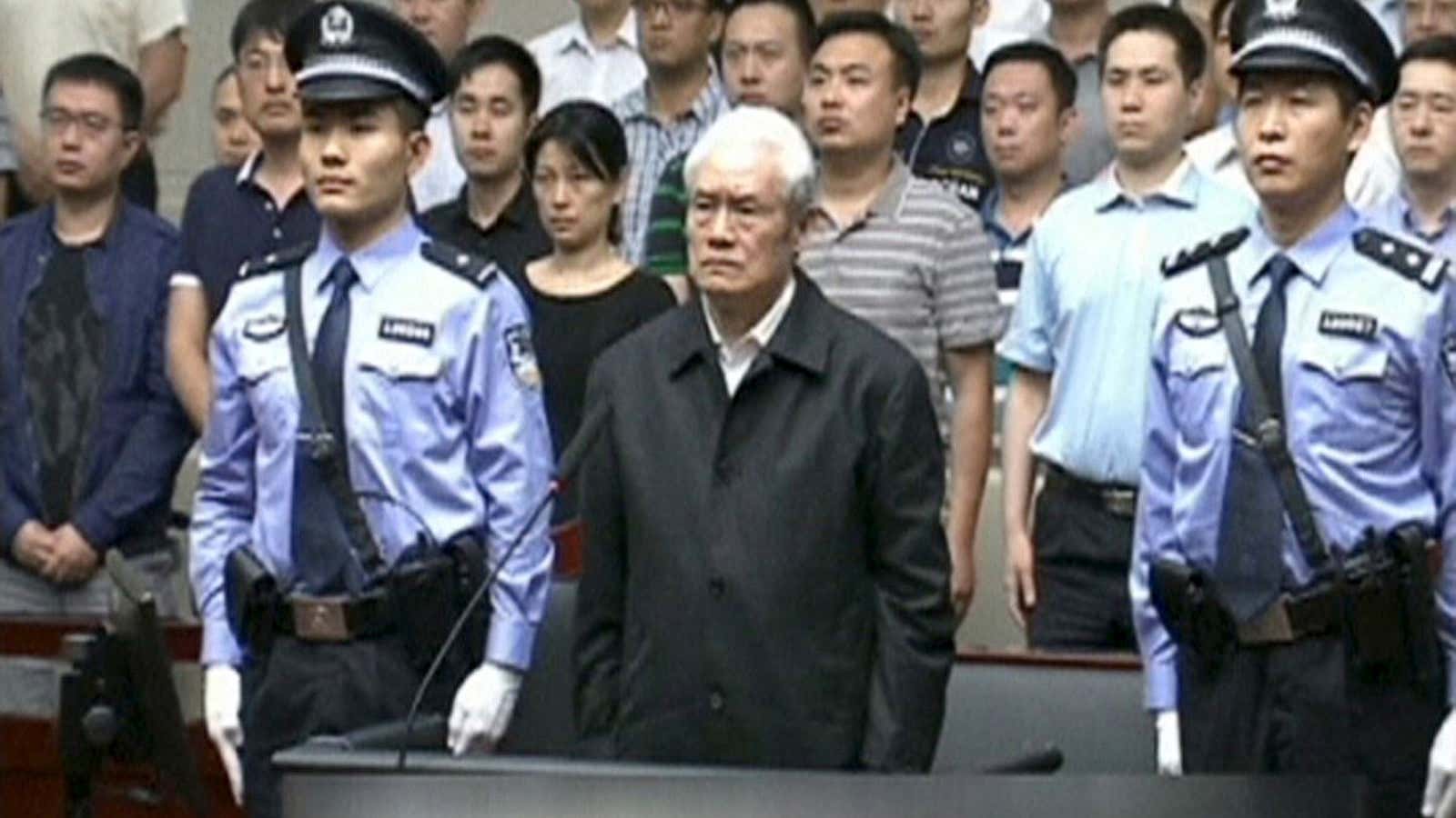 Zhou Yongkang, China’s former domestic security chief, stands between his police escorts as he listens to his sentence in a court in Tianjin, China.