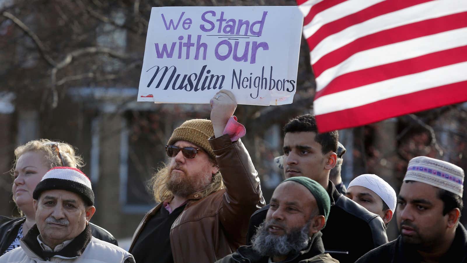 A man holds a sign in support of his Muslim neighbors as he joins Bangladeshi and Yemeni Americans to protest against the Islamic State and political and religious extremism during a rally in a Detroit suburb.