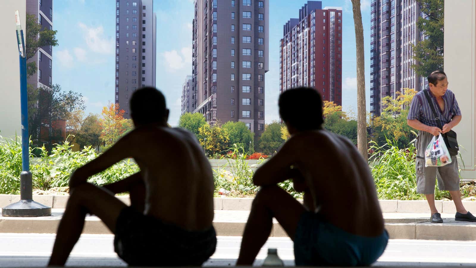 Chinese workers sit in front of a real estate hoarding. The real estate bubble is putting home ownership further out of the reach of many, even as GDP growth slows.