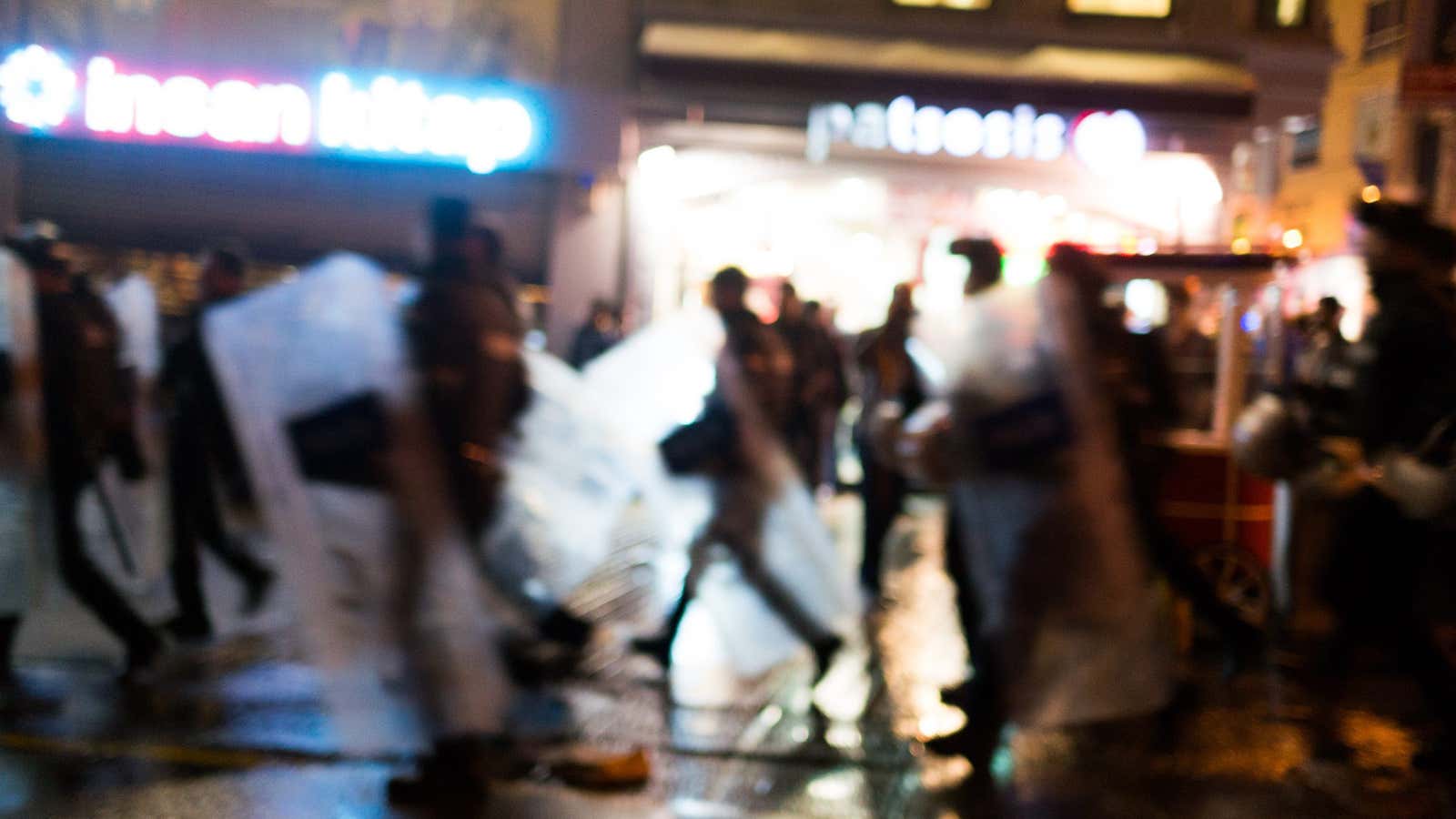 Riot police pursue protesters.