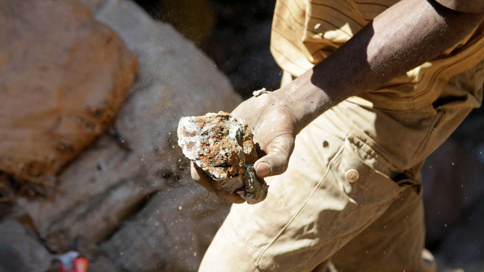 An artisanal miner carries raw ore at a former industrial copper-cobalt mine in DR Congo