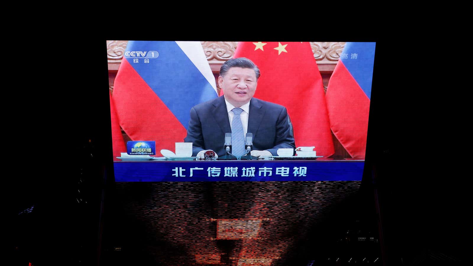 Chinese President Xi Jinping is seen on a giant screen, broadcasting news footage of a virtual meeting between him and Russian President Vladimir Putin, at…