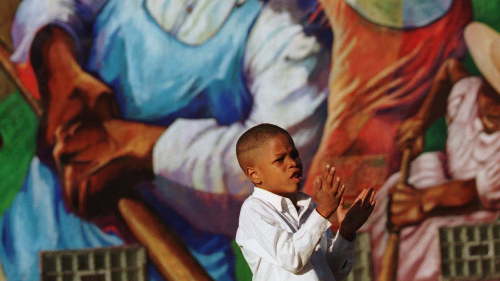 A boy in Chicago stands in front of the mural “The Great Migration.”