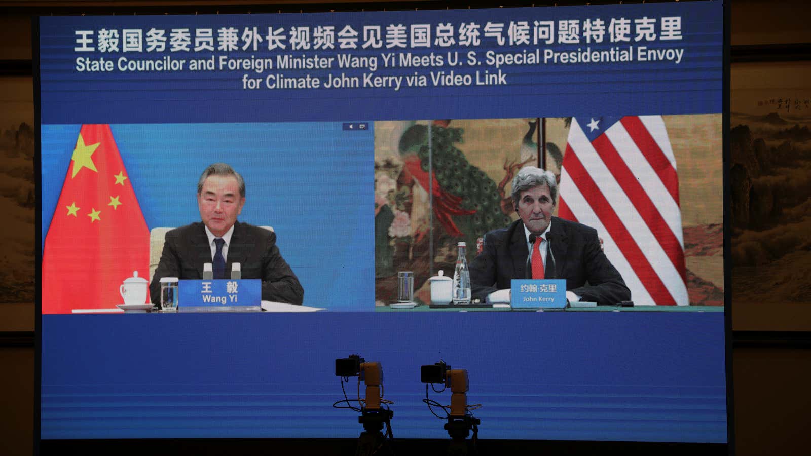 U.S. Special Presidential Envoy for Climate John Kerry is seen on a screen with Chinese State Councillor and Foreign Minister Wang Yi during a meeting…