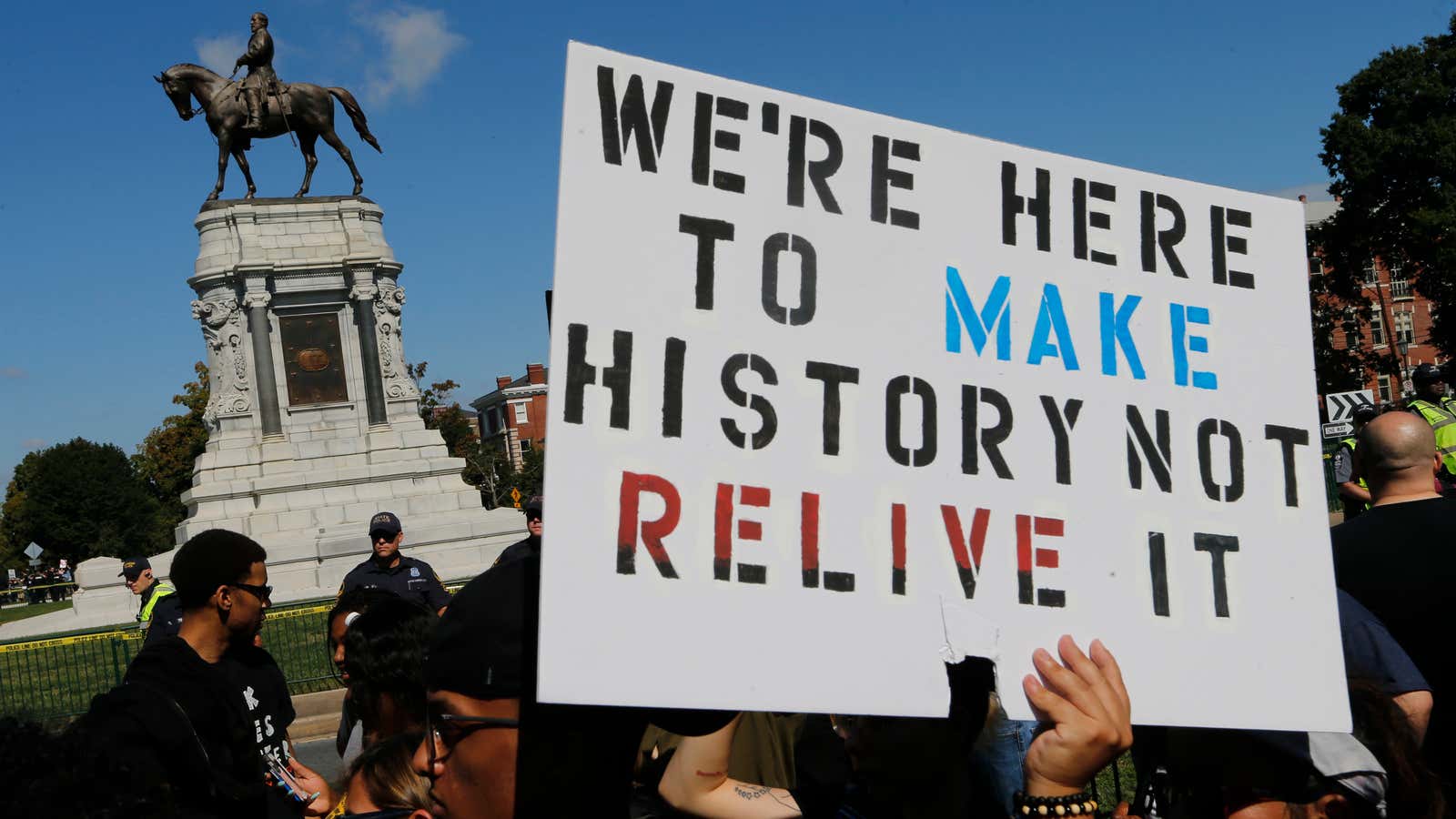 Protesters hold signs in front of the statue of Confederate General Robert E. Lee on Monument Avenue in Richmond, Va., on Sept. 16, 2017.