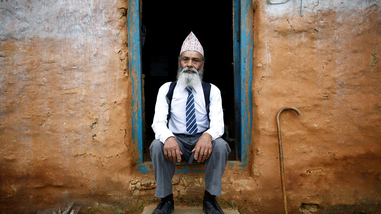 Kami, poses for a picture wearing his school uniform at the door of his one-room house.