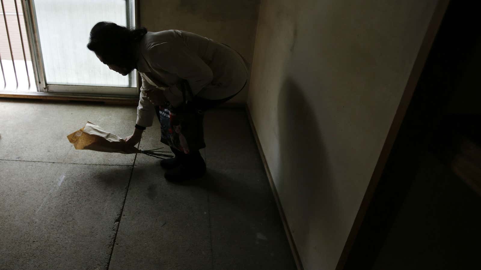 A landlord in Tokyo lays flowers where the body of an 85-year-old man was found a month after he had died.