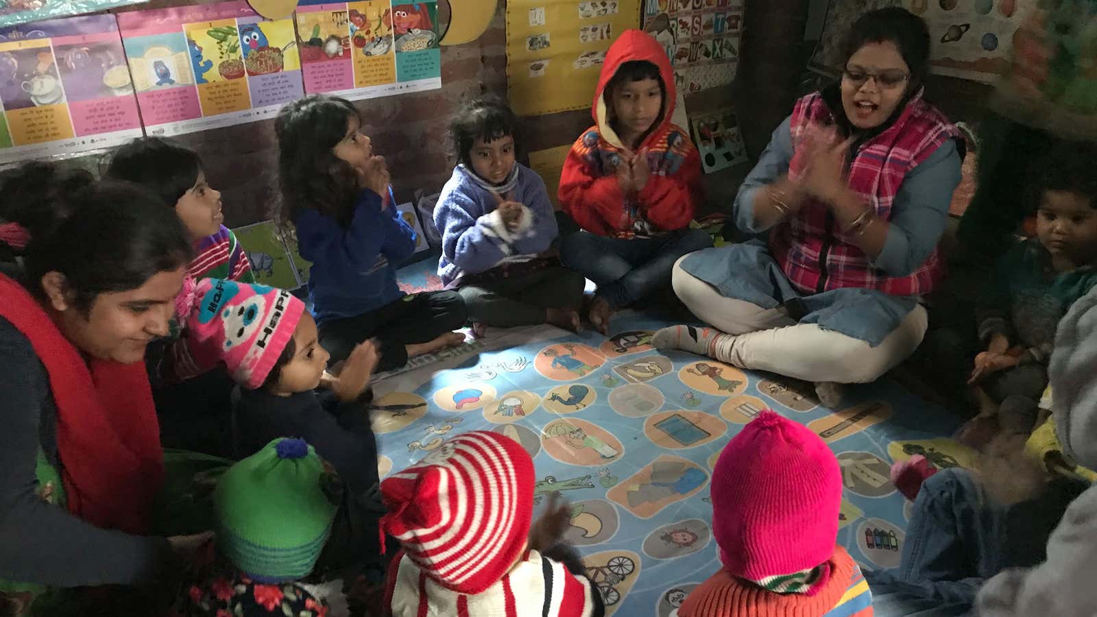 Kids play with their anganwadi worker at the anganwadi center in Ali Village.