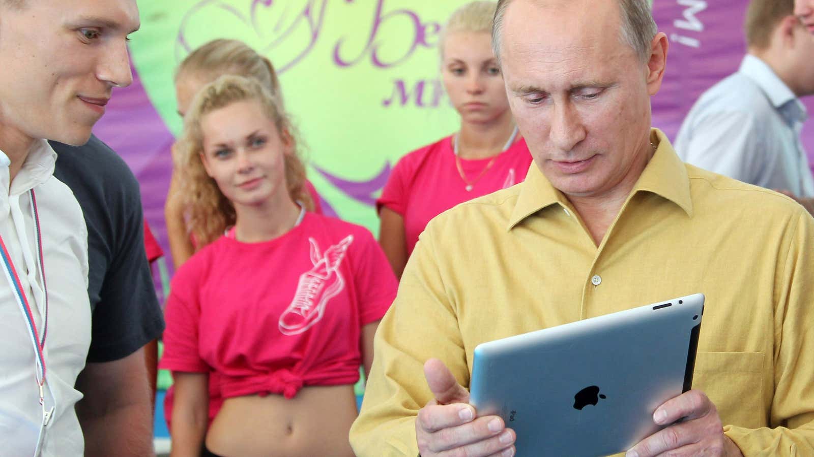 Russian President Vladimir Putin (R) holds an iPad as he talks to participants of a forum of pro-Kremlin youth groups.