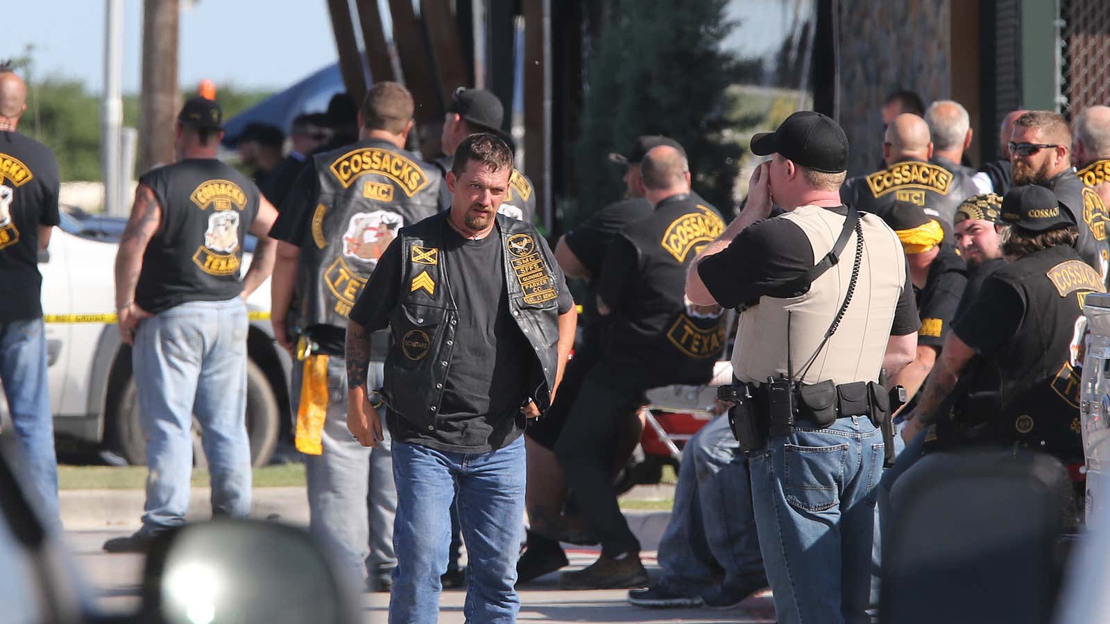 People stand as officers investigate a shooting in the parking lot of the Twin Peaks restaurant Sunday, May 17, 2015, in Waco, Texas.