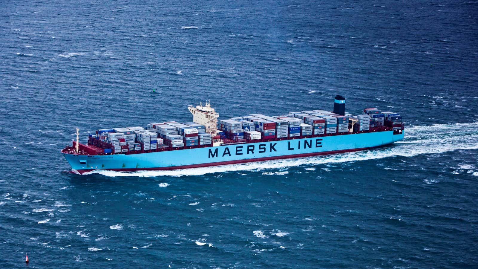 A Maersk container ship cuts through choppy seas.