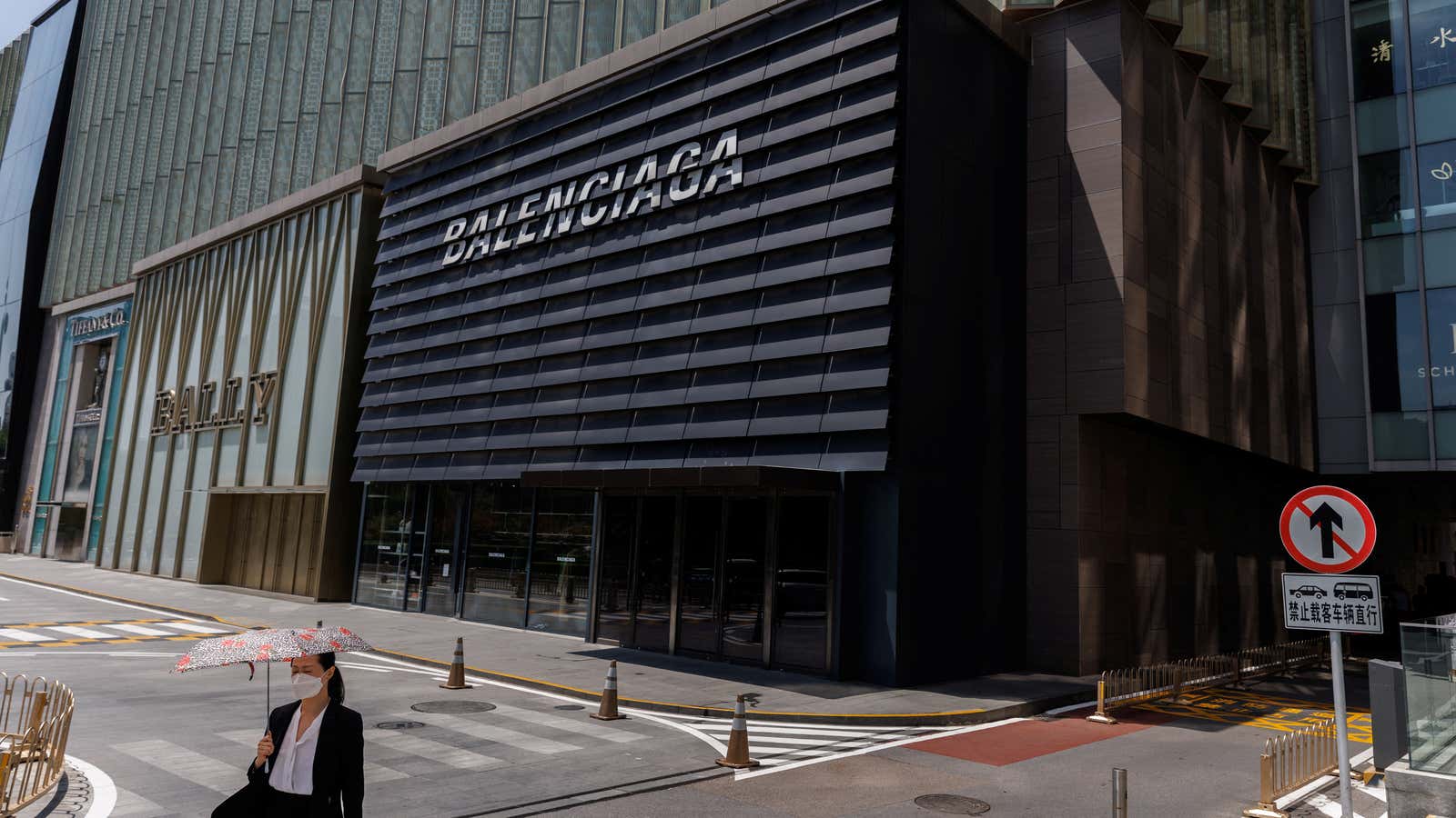 A woman walks past Bally and Balenciaga boutiques in a shopping area in Beijing on July 14, 2022.