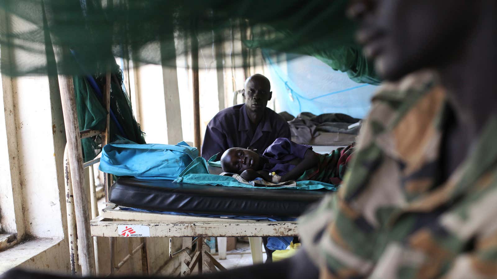 A child sick with malaria and from malnutrition lies on a bed in a hospital in South Sudan.