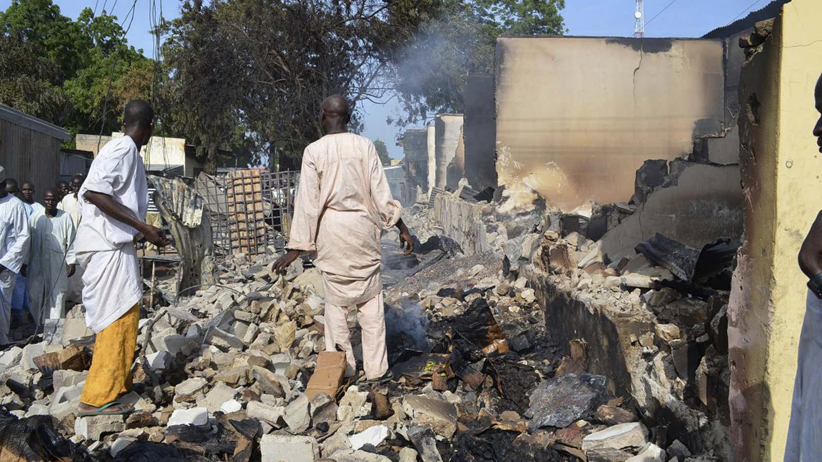 Two men walk in the rubble after Boko Haram militants raided the town of Benisheik.