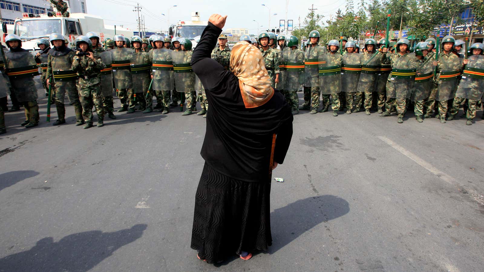 A local woman on a crutch shouts at Chinese paramilitary police in China’s Xinjiang Autonomous Region.