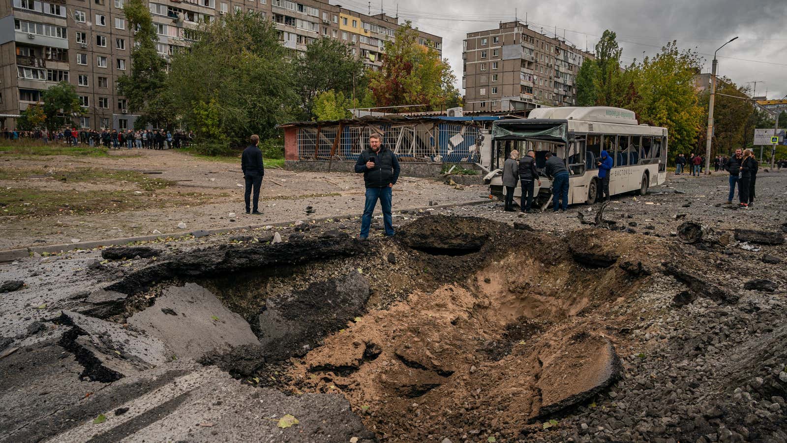 Investigators examine a crater and a damaged bus, following a missile strike in Dnipro on October 10, 2022, amid Russia&#39;s invasion of Ukraine.