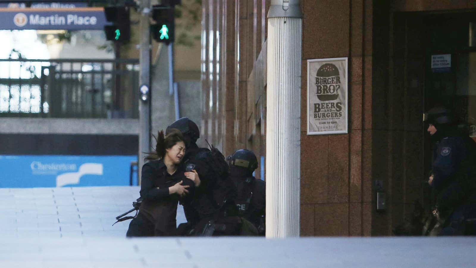 A hostage runs towards a police officer outside Lindt cafe in Sydney, Australia.