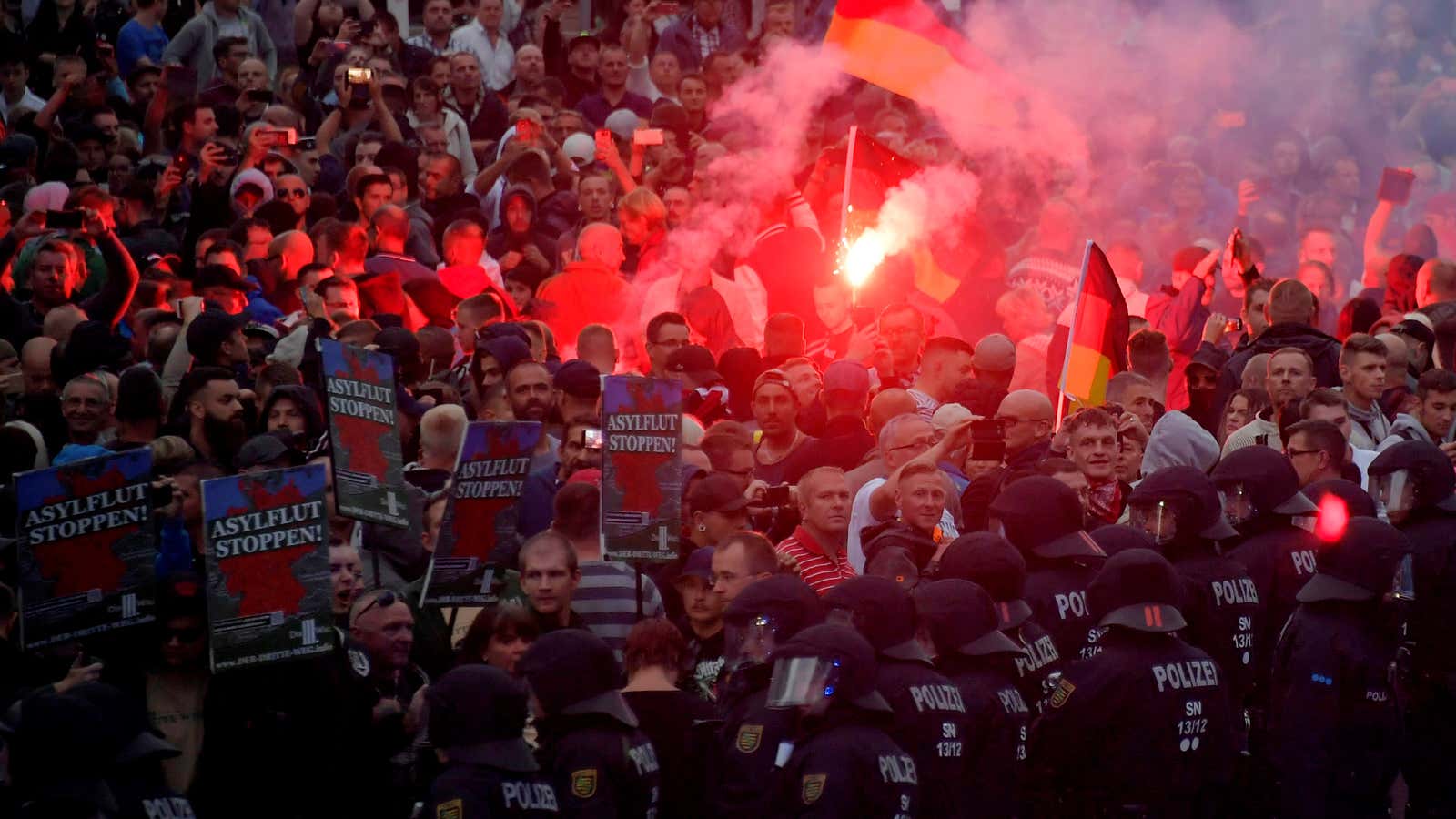 Right-wing protestors hold posters saying “stop the asylum flood” in Chemnitz.