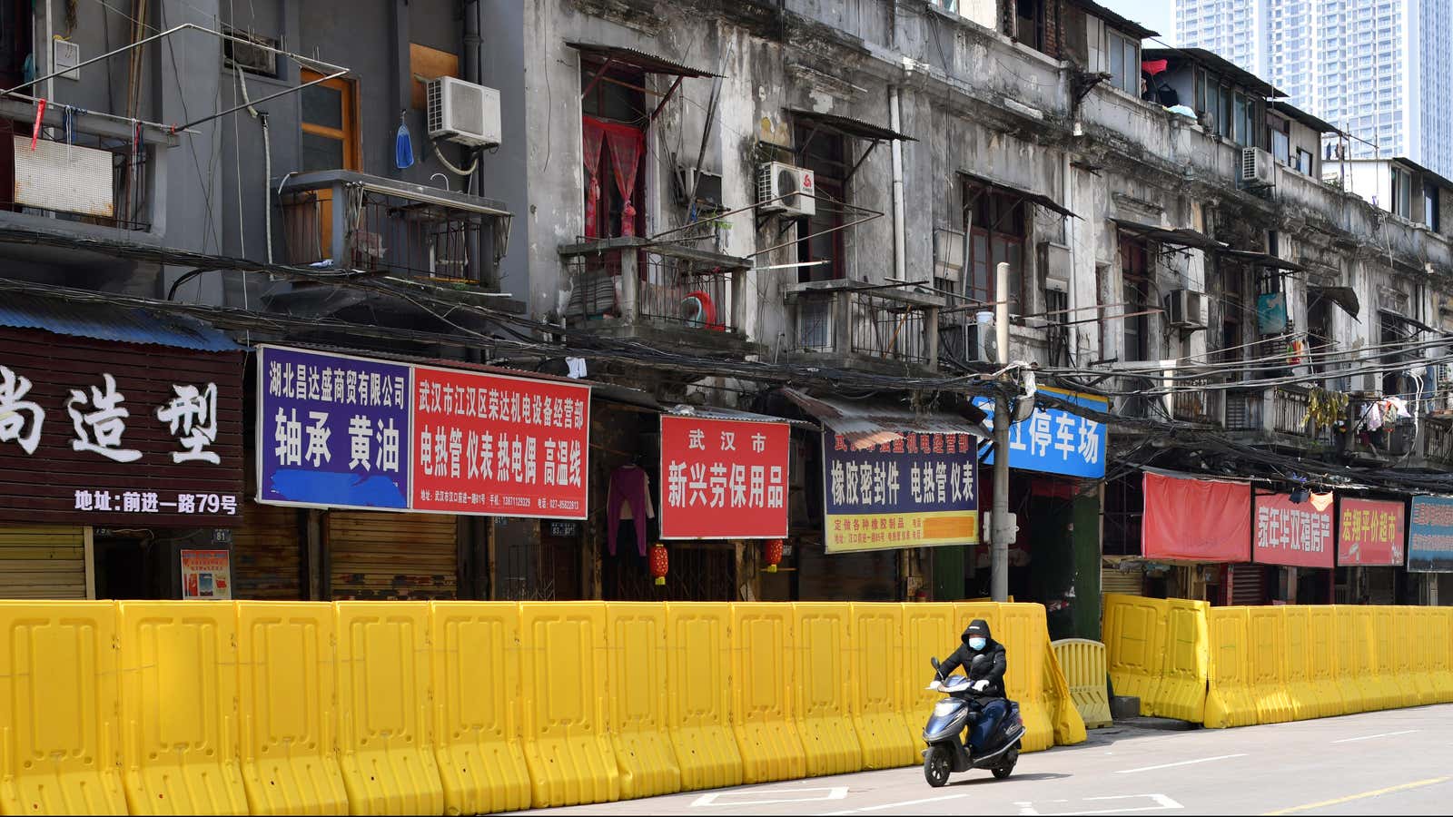 A man wearing a face mask rides past shops blocked by barricades in Wuhan, the epicenter of the novel coronavirus.