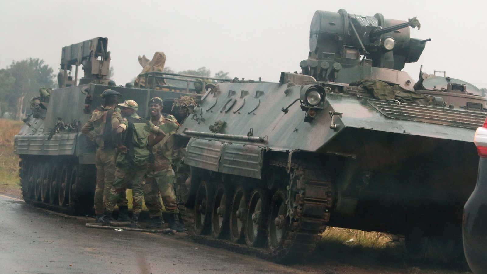 Soldiers stand beside military vehicles just outside Harare on Tuesday Nov. 14.