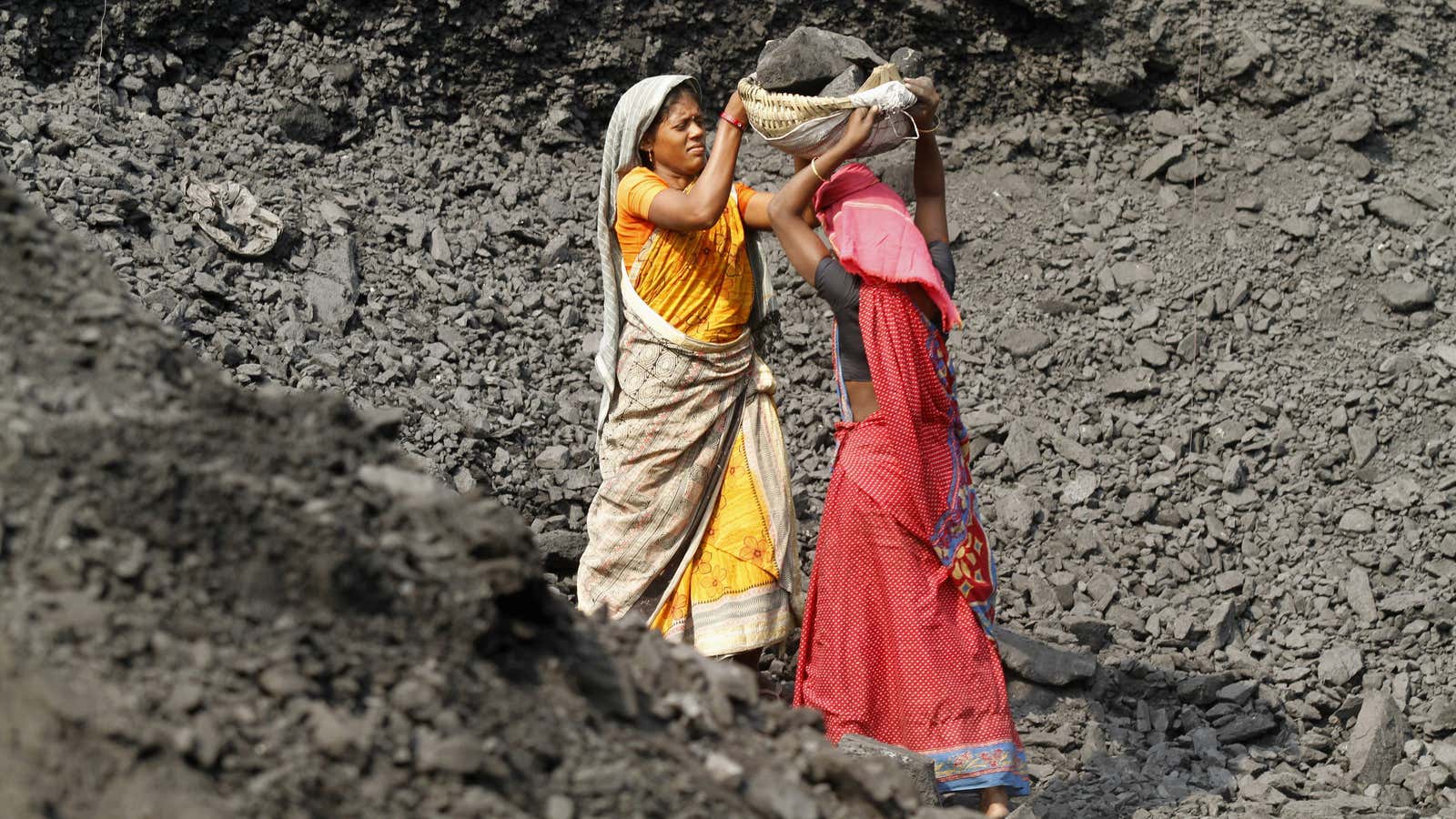 Labourers carry coal at a stockyard of an underground coal mine in the Mahanadi coal fields at Dera, near Talcher town in the eastern Indian…