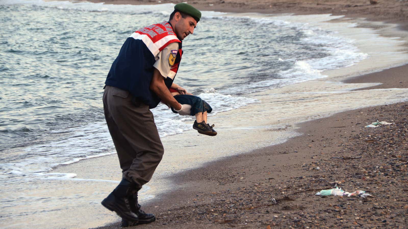 A paramilitary police officer carries the lifeless body of Syrian refugee Alan Kurdi.