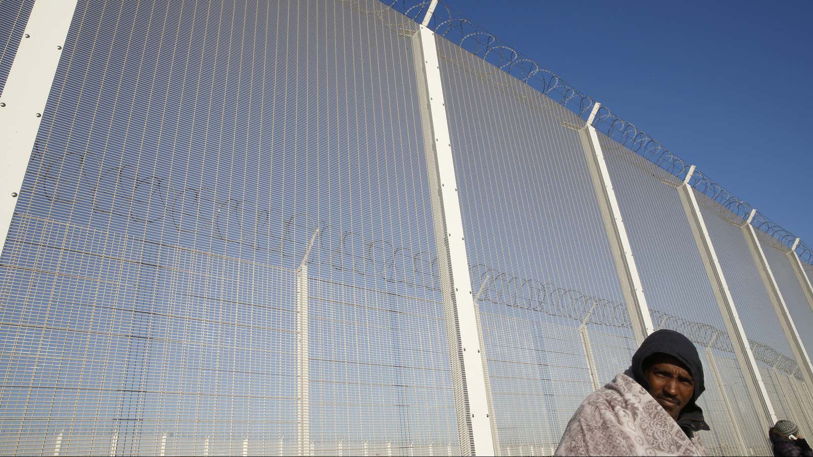 Mickael, a migrant from Eritrea, sits close to a security fence in Calais, France.