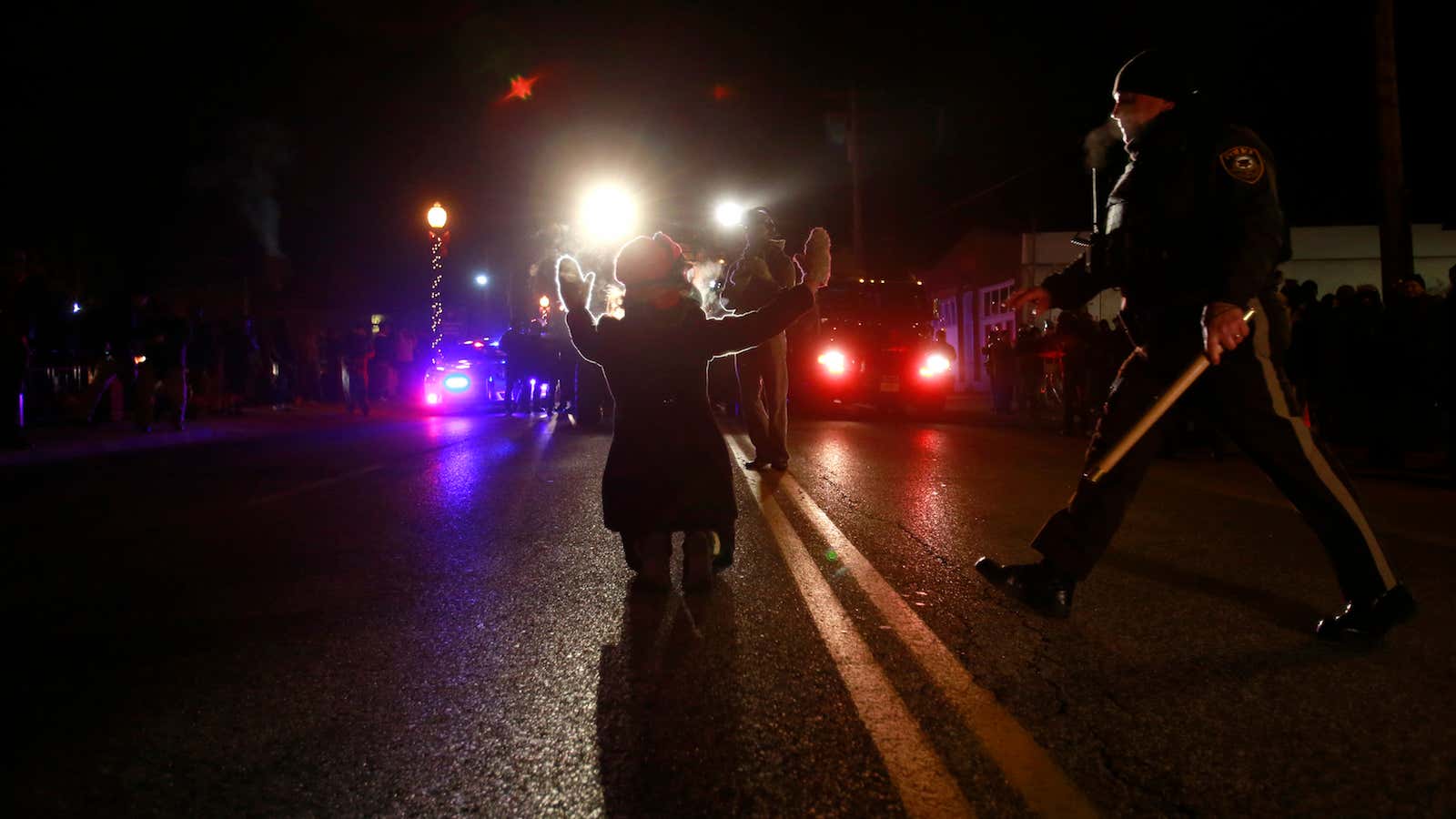 A police officer moves in to arrest a protester on her knees in front of police cars in Ferguson, Missouri, November 25, 2014.