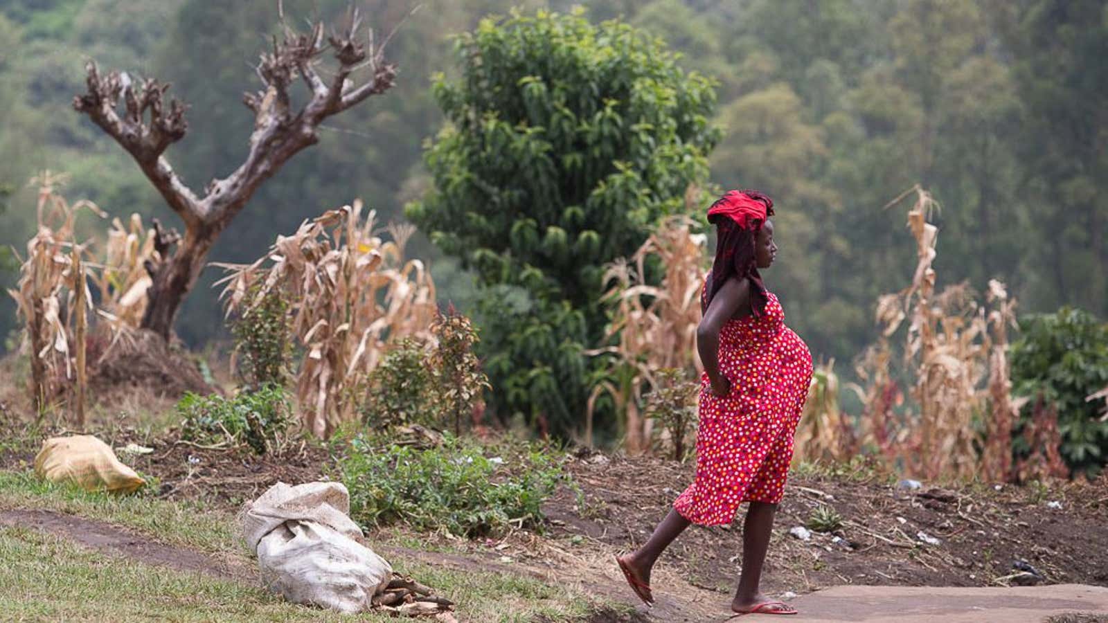 A pregnant woman walks toward the Kibiito Health Center IV waiting area for expectant mothers.