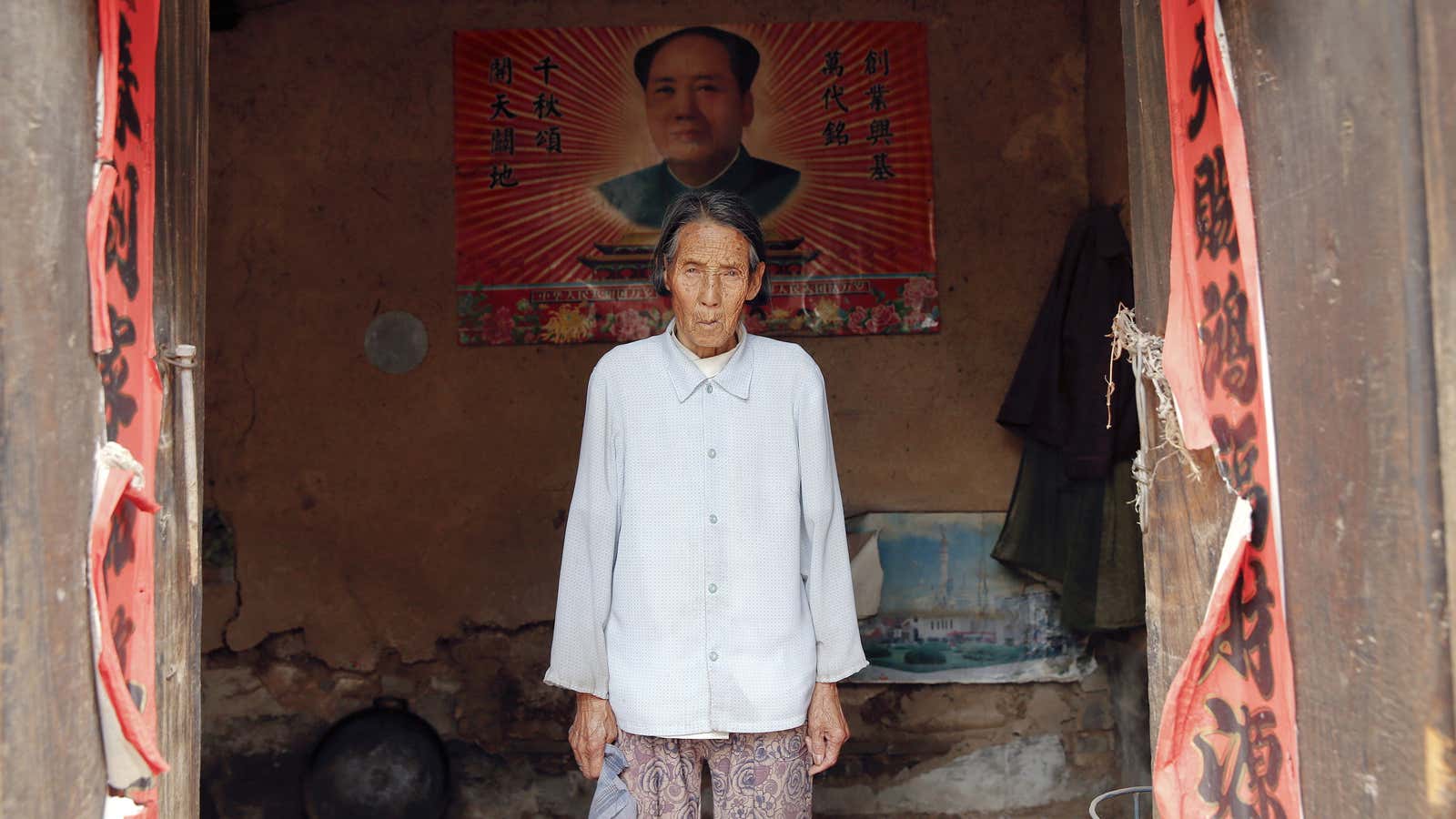 Chinese former “comfort woman” Ren Lane poses in front of a poster of China’s late Chairman Mao Zedong.