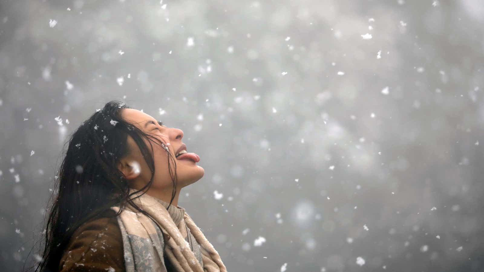 A woman tries to catch snowflakes with her tongue.