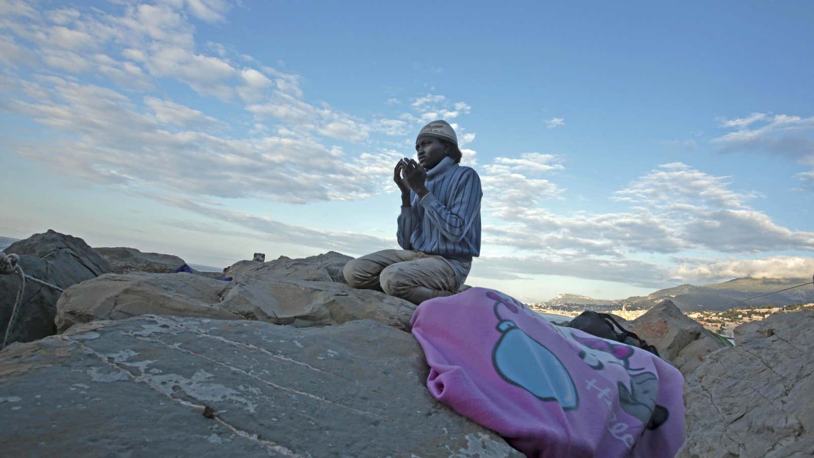 A migrant prays at sunrise on the rocks of the seawall at the Saint Ludovic border crossing on the Mediterranean Sea between Vintimille and Menton