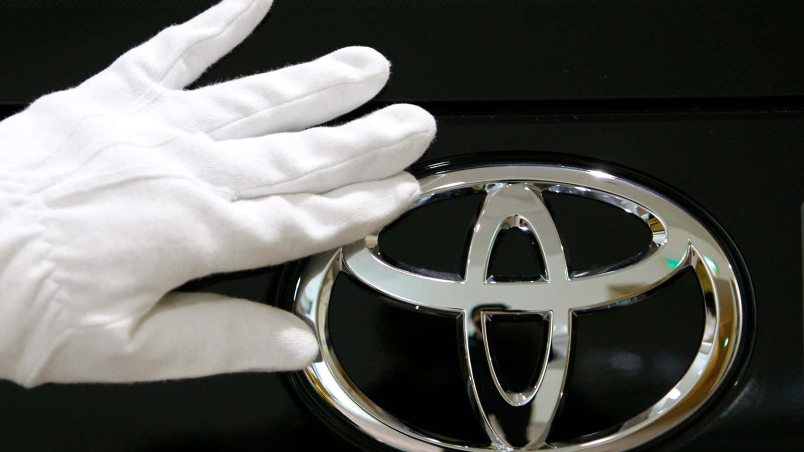 A staff of Toyota Motor Corp&#39;s showroom cleans the logo on a car in Tokyo.