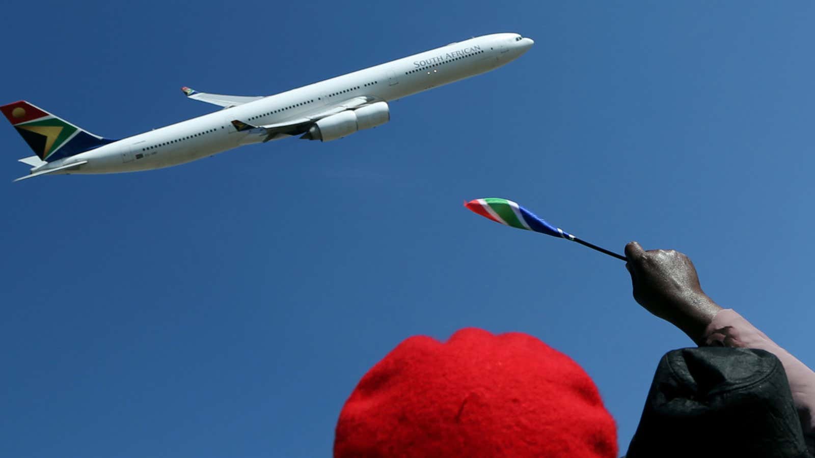 Ruling party supporters wave for a South African Airways Airbus flyby during the inauguration of the Union Building in Pretoria, South Africa, Saturday, May 24,…