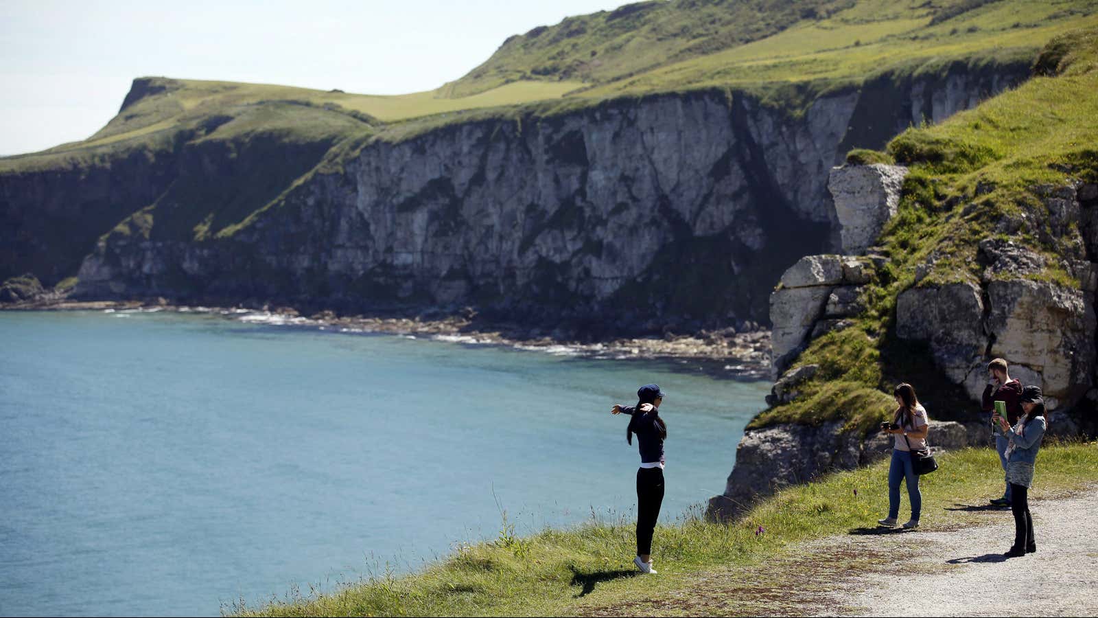 In this photo taken June 13, 2014, tourists pose for photographs on the North Antrim Coast close to Carrick-a-Rede Rope Bridge lies Larrybane headland. Larrybane…