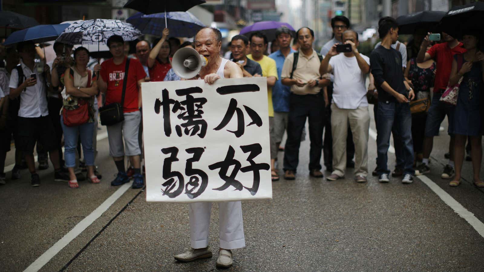 A man in Mong Kok holds up a sign encouraging democracy protesters, “Don’t be weak.”