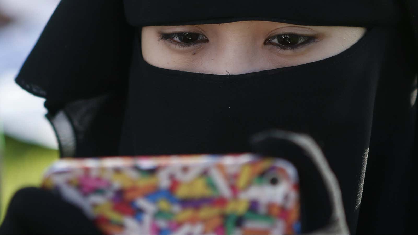 A Filipino Muslim looks at her mobile phone while waiting for morning prayers to begin, during the celebration of Eid al-Fitr, marking the end of…