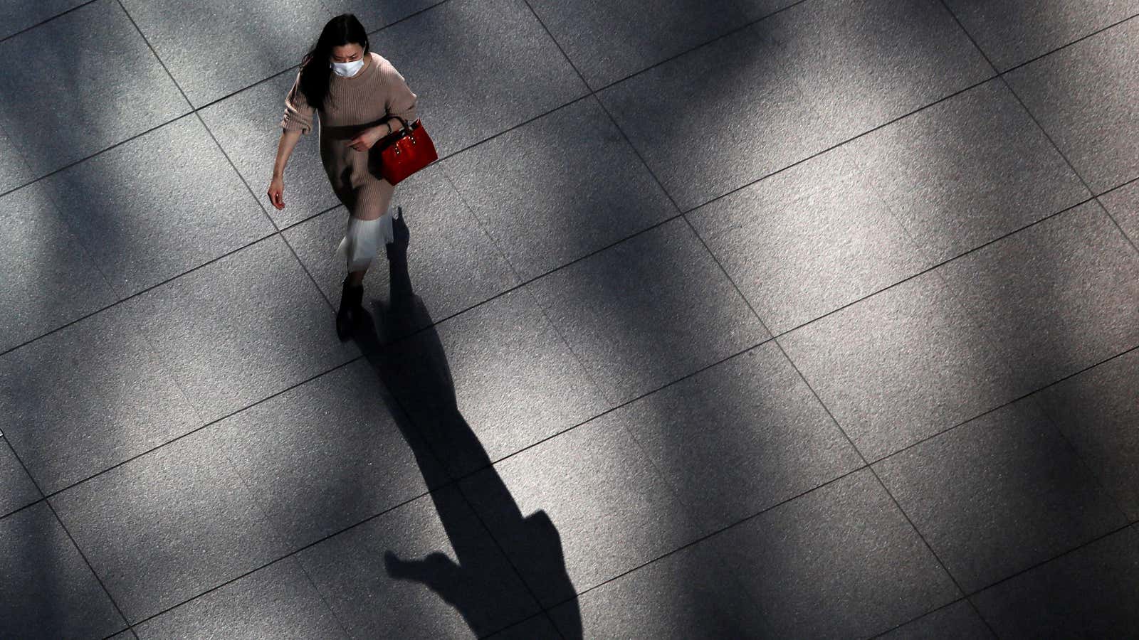 A woman wearing a protective face mask walks inside a buildng at a business district, amid the coronavirus disease (COVID-19) outbreak, in Tokyo, Japan November…