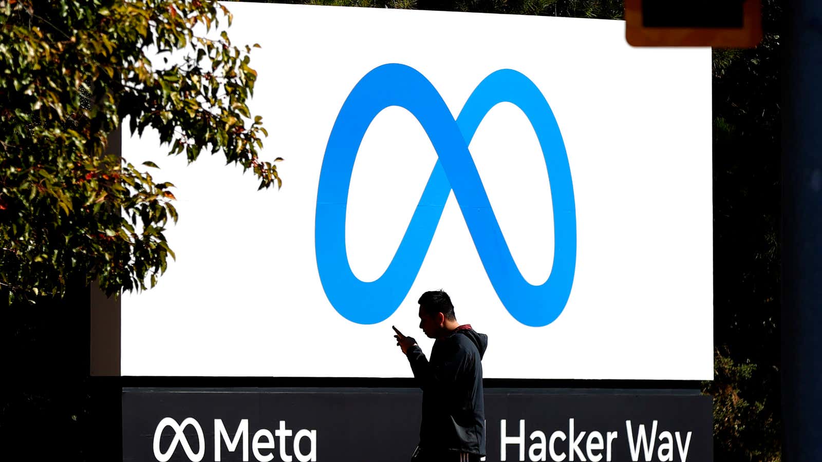 A pedestrian walks in front of a Meta sign in Menlo Park, California.