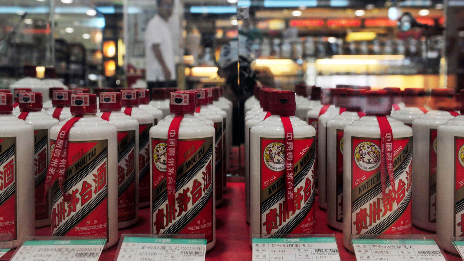 A customer walks past a glass case displaying Maotai liquors with different price tags at a supermarket in Shenyang, Liaoning province August 8, 2012. The…
