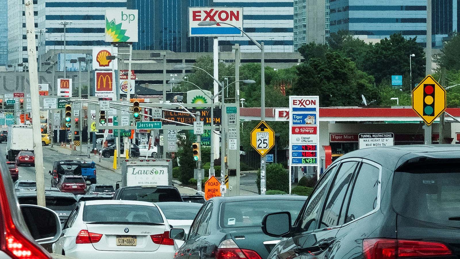 People drive their cars near Exxon and BP gas stations at the exit of the Holland Tunnel during the start of the Memorial Day weekend,…