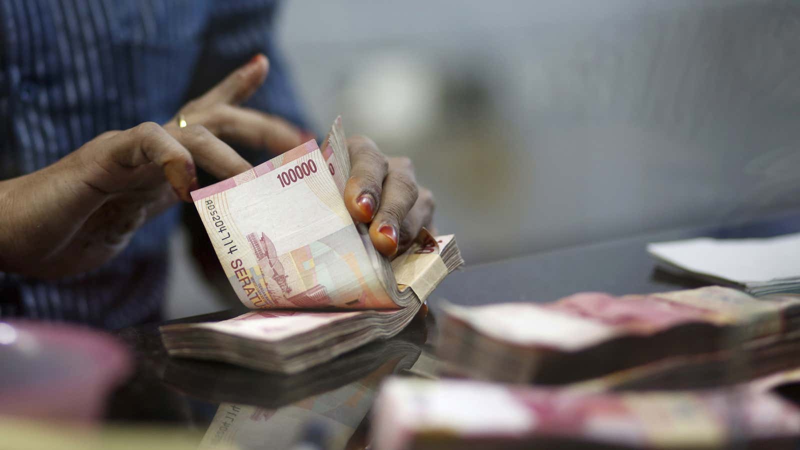 A teller counts Indonesian Rupiah notes inside a money changer in Jakarta, Indonesia.