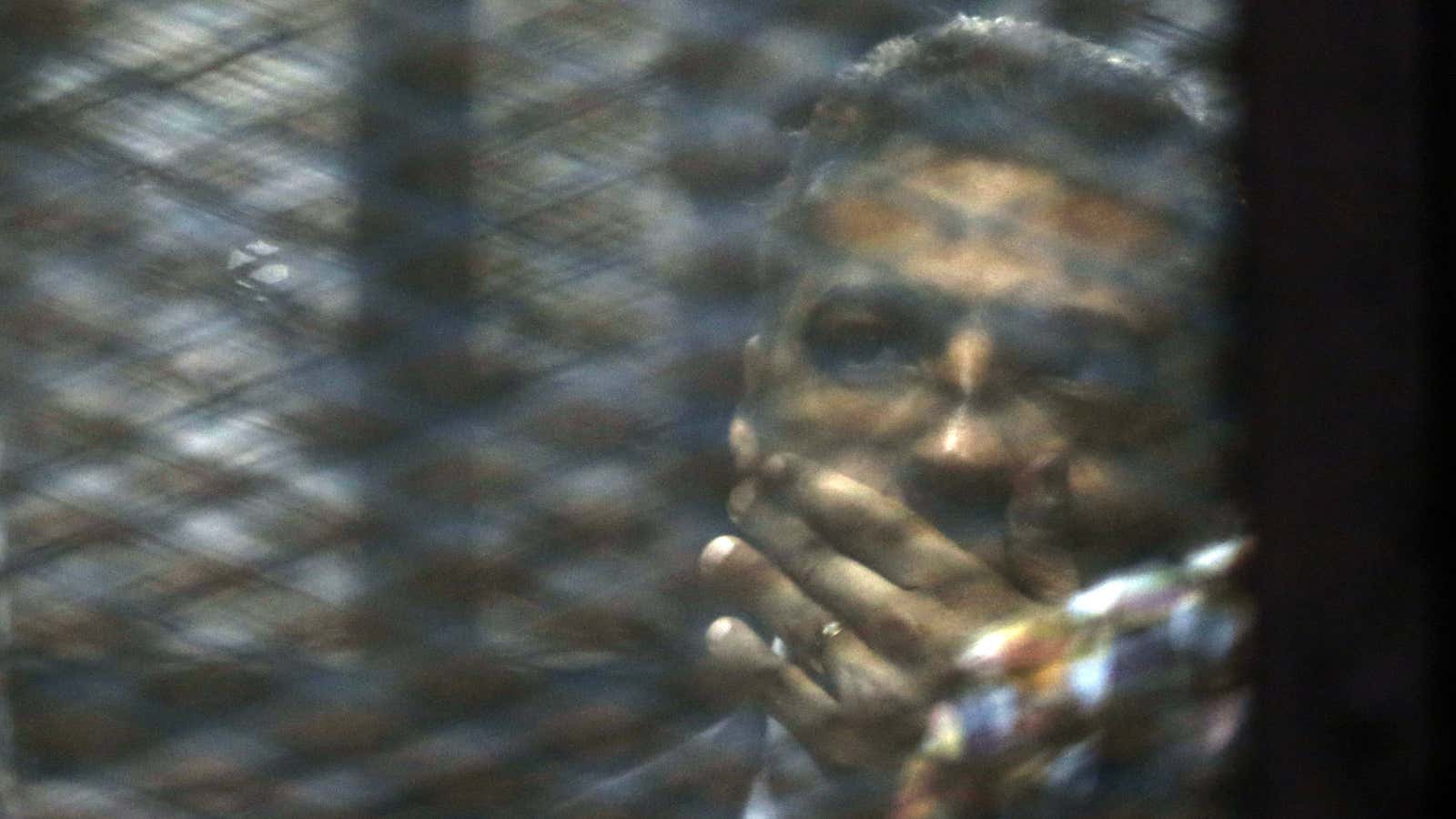 Mohamed Fahmy listens to the verdict from a cell in the courtroom.