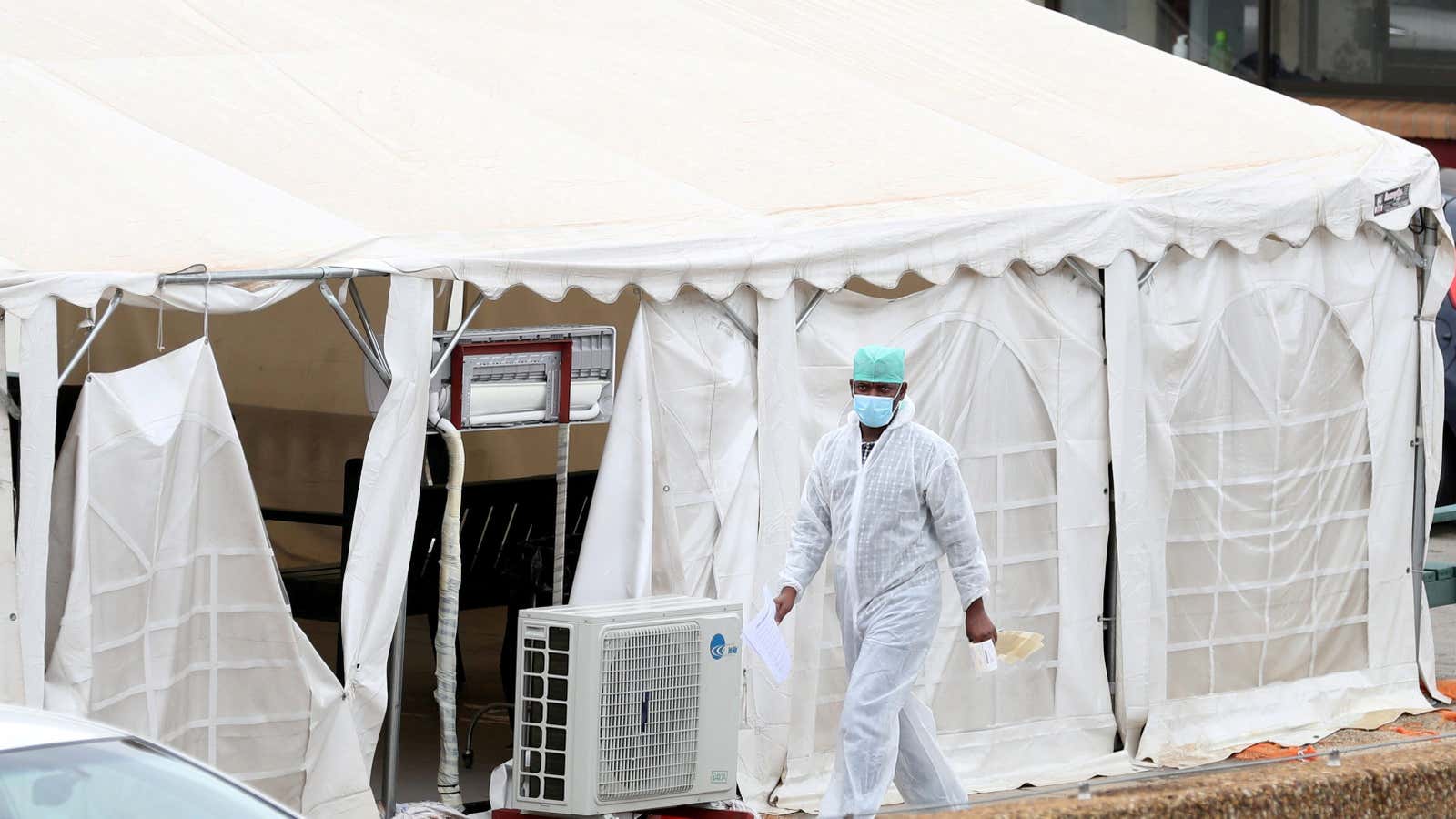 A health worker walks past tents erected for Covid-19 patients at the parking lot of the Steve Biko Academic Hospital in Pretoria, South Africa, Jan. 11, 2021.