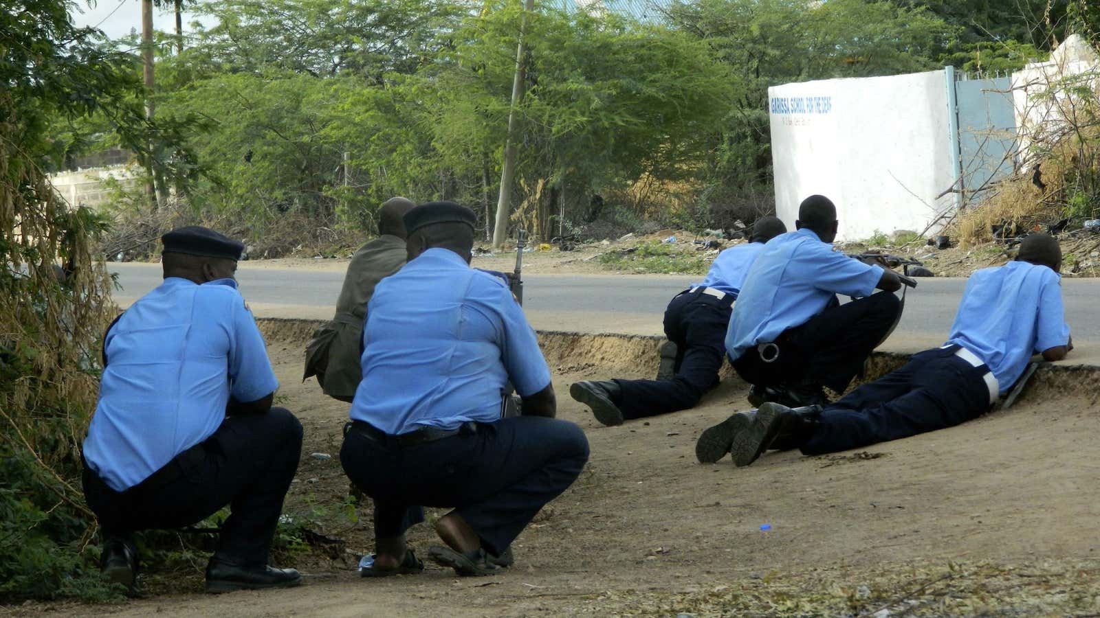 Kenyan police take cover outside the Garissa University College during an attack by gunmen.