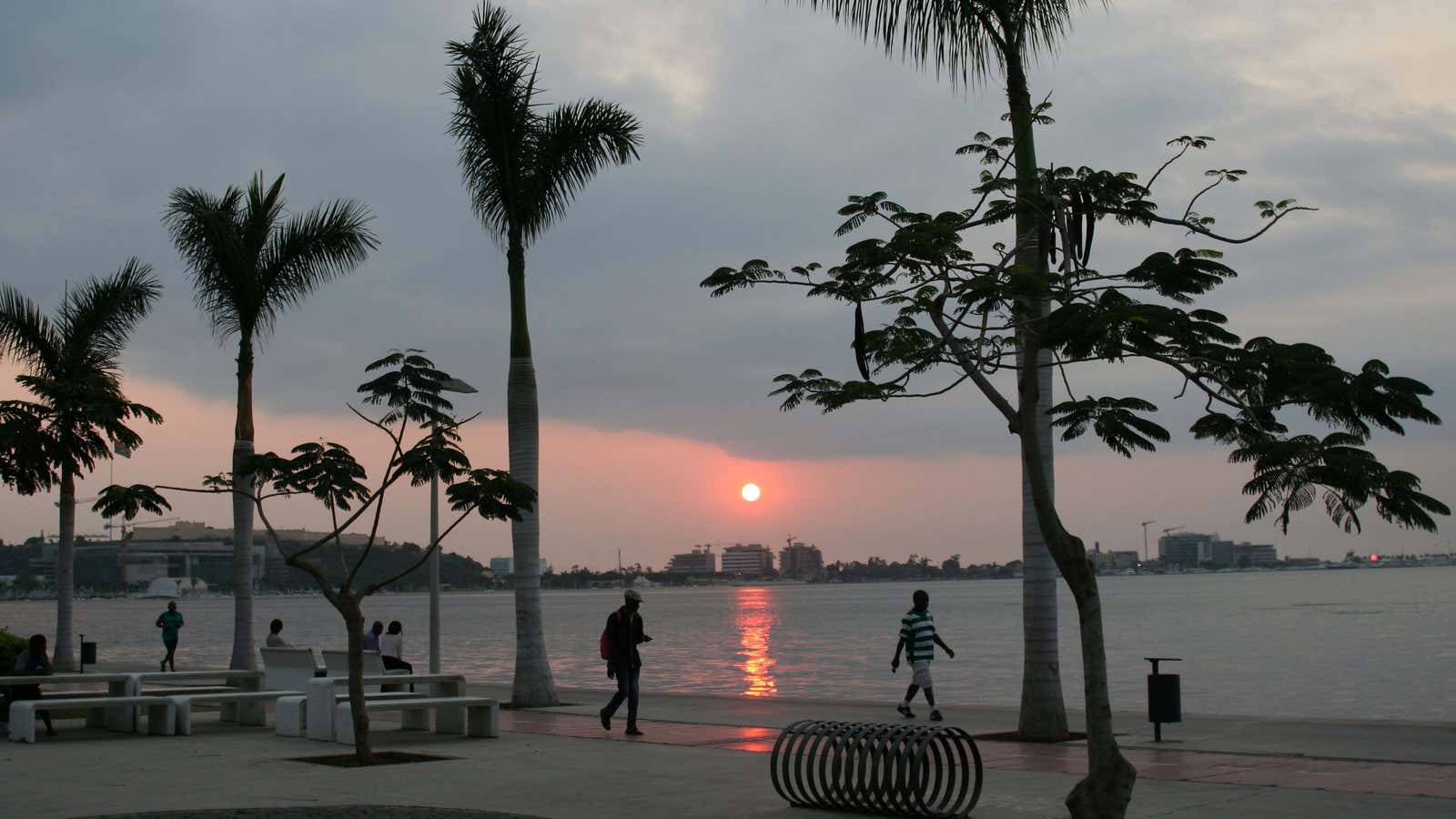 Locals walk along the beach during sunset in Luanda, Angola