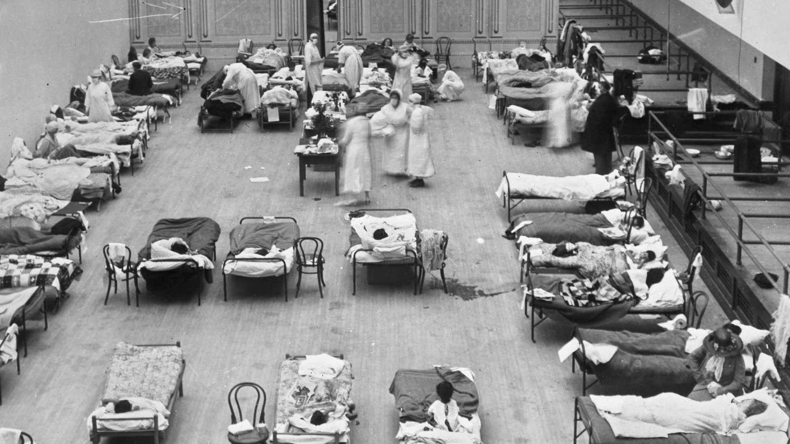 In this 1918 photo  volunteer nurses from the American Red Cross tend to influenza patients in the Oakland Municipal Auditorium, used as a temporary hospital.