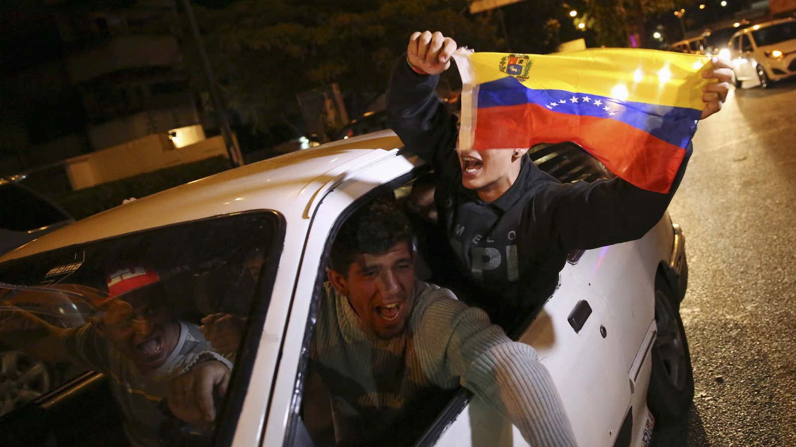 Supporters of the opposition Democratic Unity coalition wave a Venezuelan national flag from a car while they celebrate their victory on a street in Caracas.