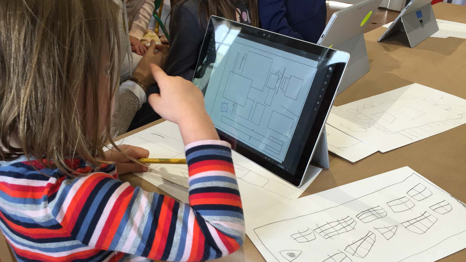 Three-year-old Ashton Hutchinson looks over shapes for a building design that she will cut out of cardboard with a laser cutter.